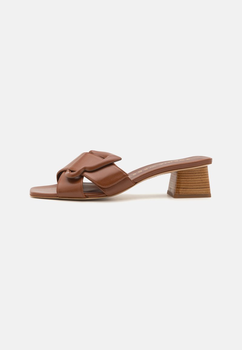 Mules abiertos de cuero marrón con diseño de tiras cruzadas, con un tacón bloque de madera de tamaño medio y textura suave.