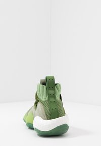 Zielony but sportowy wykonany z mieszanki zamszu i siateczki, z wysoką cholewką, teksturowaną górą i charakterystyczną białą podeszwą.