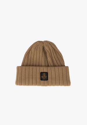 Cappello beanie lavorato a maglia color beige con un design a coste e un risvolto. Presenta una patch quadrata nera con un grafico di un cane e il testo "RekgillWear".