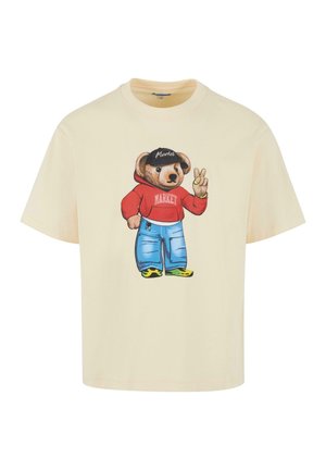 Crème katoenen t-shirt met een cartoonbeer in een rode hoodie met de tekst "MARKET", blauwe spijkerbroek en zwarte schoenen, met een vredesteken gebaar.