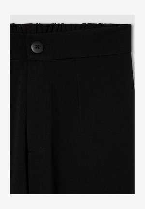 Czarne spodnie z elastycznym pasem, wyposażone w zapięcie na guzik oraz dwie przednie kieszenie. Gładki, lekko teksturowany materiał.