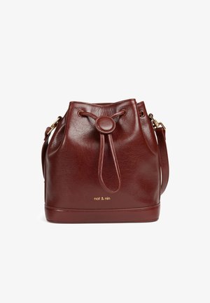 Sac seau en cuir bordeaux avec fermeture à cordon, logo en relief et texture lisse. Présente un accent doré et une sangle ajustable.