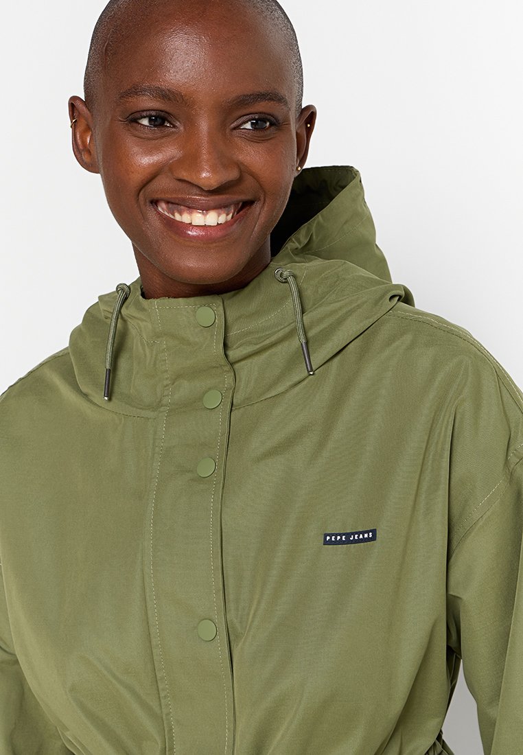 Oliwkowa kurtka z kapturem, wykonana z lekkiego materiału, z zatrzaskami, regulowanym kapturem i małą naszywką z logo na piersi.