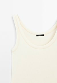 Canotta senza maniche di colore crema chiaro con scollo rotondo, realizzata in un tessuto morbido; presenta una leggera texture a costine e orlo cucito.