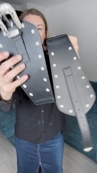 Μαύρη δερμάτινη ζώνη με ασημένιους στύλους, ορθογώνιο σχήμα, ρυθμιζόμενο λουράκι, διακοσμητική πόρπη στην κορυφή. Υφή επιφάνειας.