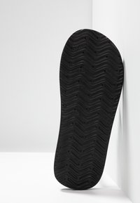 Suola della scarpa con una superficie in gomma nera texturizzata, caratterizzata da un motivo a zigzag per un'ottima aderenza e un bordo della punta arrotondato.