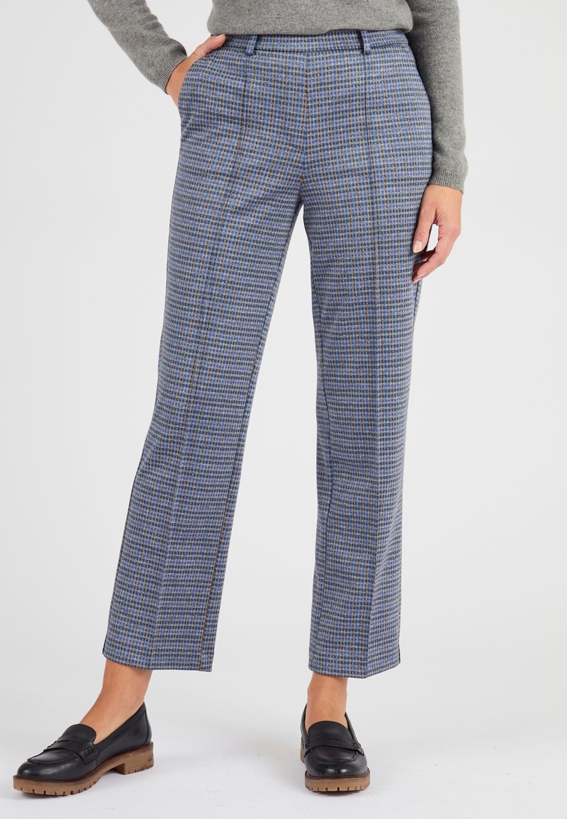 Pantaloni a quadri in tonalità blu e grigia, con un design a gamba dritta, tasche laterali e una texture liscia. Abbinati a mocassini neri.