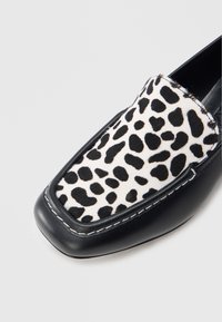 Μαύρα δερμάτινα μοκασίνια με επάνω μέρος σε λευκό και μαύρο λεοπάρ μοτίβο, με λεία υφή και αντίθετη λευκή ραφή. Σχέδιο με τετράγωνη μύτη.