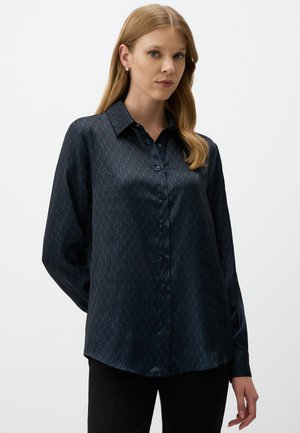 Dark blue satin blouse featuring a diamond pattern, pointed collar, and button-down front. Long sleeves with a relaxed fit.
