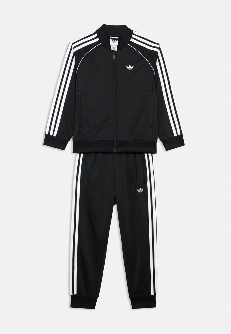 Čierny teplákový komplet z hladkej látky, obsahujúci bundu na zips s bielymi pruhmi a zodpovedajúce nohavice s elastickým pásom a vreckami.