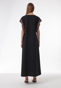 Zwarte maxi-jurk met korte mouwen, versierd met kleurrijke decoratieve kralen, met een eenvoudig, losvallend ontwerp en een zachte textuur van de stof.