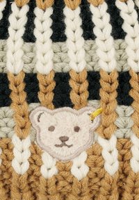 Knitted textile with alternating stripes in black, cream, beige, and brown. Features a plush embroidered bear patch with facial details.