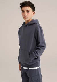Granatowa bluza z kapturem z miękkiego materiału, z kieszenią z przodu, regulowanym kapturem ze sznurkiem oraz ściągaczami przy nadgarstkach, w komplecie z pasującymi spodniami.