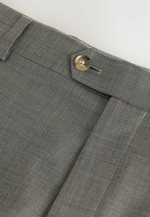 Harmaat kangashousut, joissa on teksturoitu pinta, napin suljenta ja siisti ommeltu helma. Läheltä otettu kuva vyötärönauhasta.