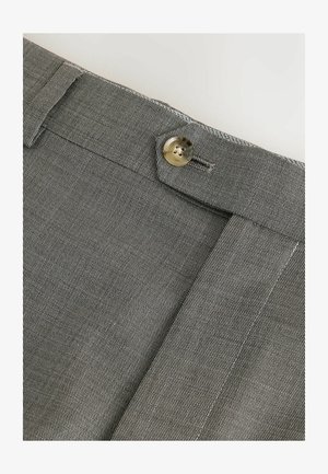 Szare spodnie z tkaniny o fakturowanej powierzchni, z zapięciem na guzik i starannie obszytym dołem. Zbliżenie na pas.