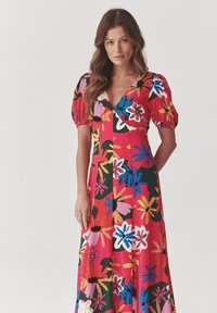 Puffærmet kjole i lysende rød med et blomsterprint i pink, blå, grøn og gul. Har en dyb V-hals og en flydende silhuet.