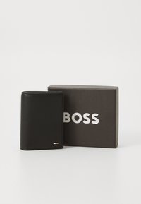 Black leather wallet with a textured finish, features a small brand logo and detail accents, placed beside a gray box with white lettering.