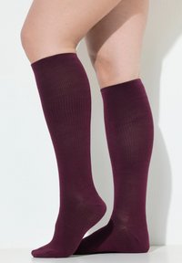 Calcetines de color marrón burdeos hasta la rodilla con una textura acanalada, que presentan punteras y talones reforzados, mostrando un material suave y un diseño ajustado.