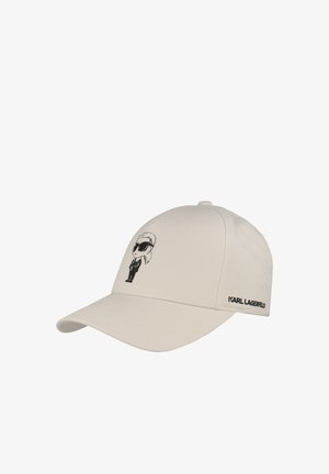 Beige baseballpet met zwarte cartoonafbeelding van een persoon met een zonnebril en tekst "KARL LAGERFELD" aan de zijkant.
