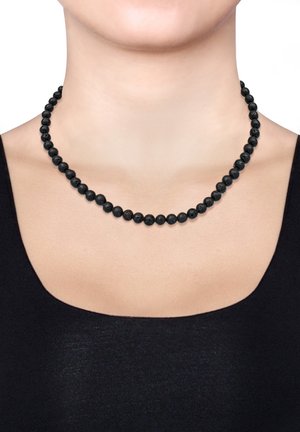 Black lava bead necklace, round textured beads alternate in size, knotted, resting on the neckline, with a simple black top below.