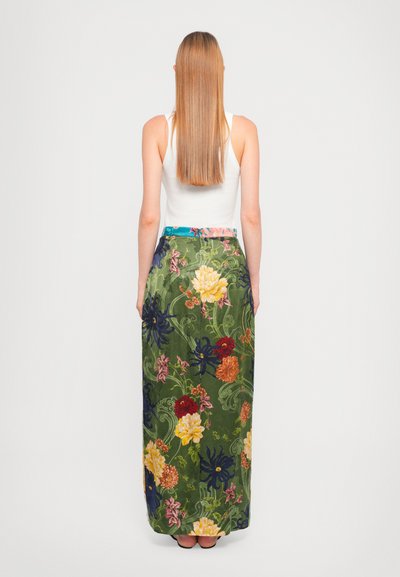 Lunga gonna floreale con base in tessuto verde, modelli di fiori multicolori e vita blu. Il design include motivi naturali.