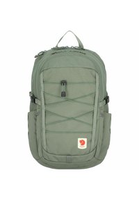 Grønn stoffryggsekk med et robust design, har mesh sidelommer, frontbungee-kord og en logopatch nederst.