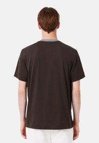 T-shirt marrone a maniche corte con scollo a costine caratterizzato da righe verdi e bianche, realizzato in un tessuto morbido con una vestibilità comoda.