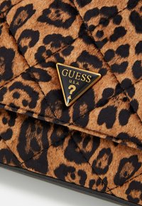 Bolso acolchado con estampado de leopardo en tonos de marrón y negro. Presenta un logo en forma de triángulo dorado con "GUESS U.S.A." en texto negro.