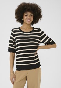 Pull à manches courtes noir et crème à rayures, avec un col rond, présentant une coupe décontractée et des poignets et un ourlet côtelés. Texture lisse.