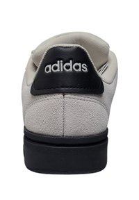 Sneaker Adidas con una morbida tomaia in suede grigio, una patch in pelle nera sul tallone con il logo bianco e una suola in gomma nera.