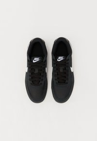 Baskets Nike noires avec une tige en tissu, logo blanc et lacets noirs. Bout rond et col rembourré, avec une semelle texturée.