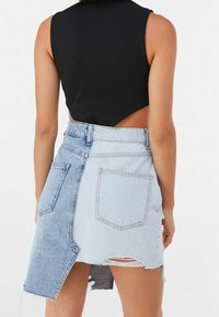 Musta ribbineuloksinen lyhyt toppi, jossa on leikattu selkäosa, yhdistetty kaksiväriseen farkkuhameeseen, jossa on repsottavat reunat ja kaksi takataskua.