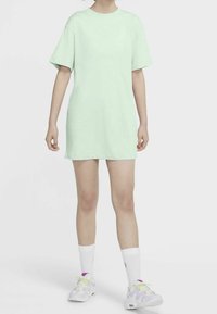 Vihreä mintunvärinen ylipitkä T-paitamekko lyhyillä hihoilla, jossa on pieni valkoinen Nike-logo rinnassa. Yhdistettynä valkoisiin sukkiin ja tennareihin.