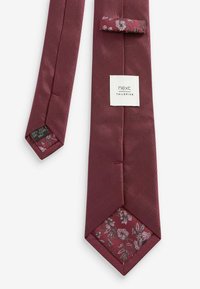 Bordeauxseide-Krawatte mit floralem Muster auf der Unterseite, ausgestattet mit einem Etikett mit der Aufschrift "next TAILORING" und einem spitzen Ende.