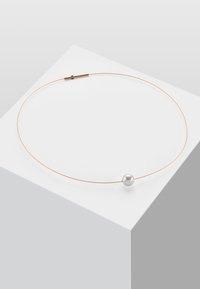 Tynn choker av roséfarget metall med en enkelt rund hvit perle i midten. Minimalistisk design med jevn tekstur og subtil glans.