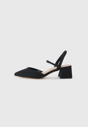 Black slingback heel with a pointed toe, textured fabric, and a chunky geometric heel. Features crossed straps at the ankle.