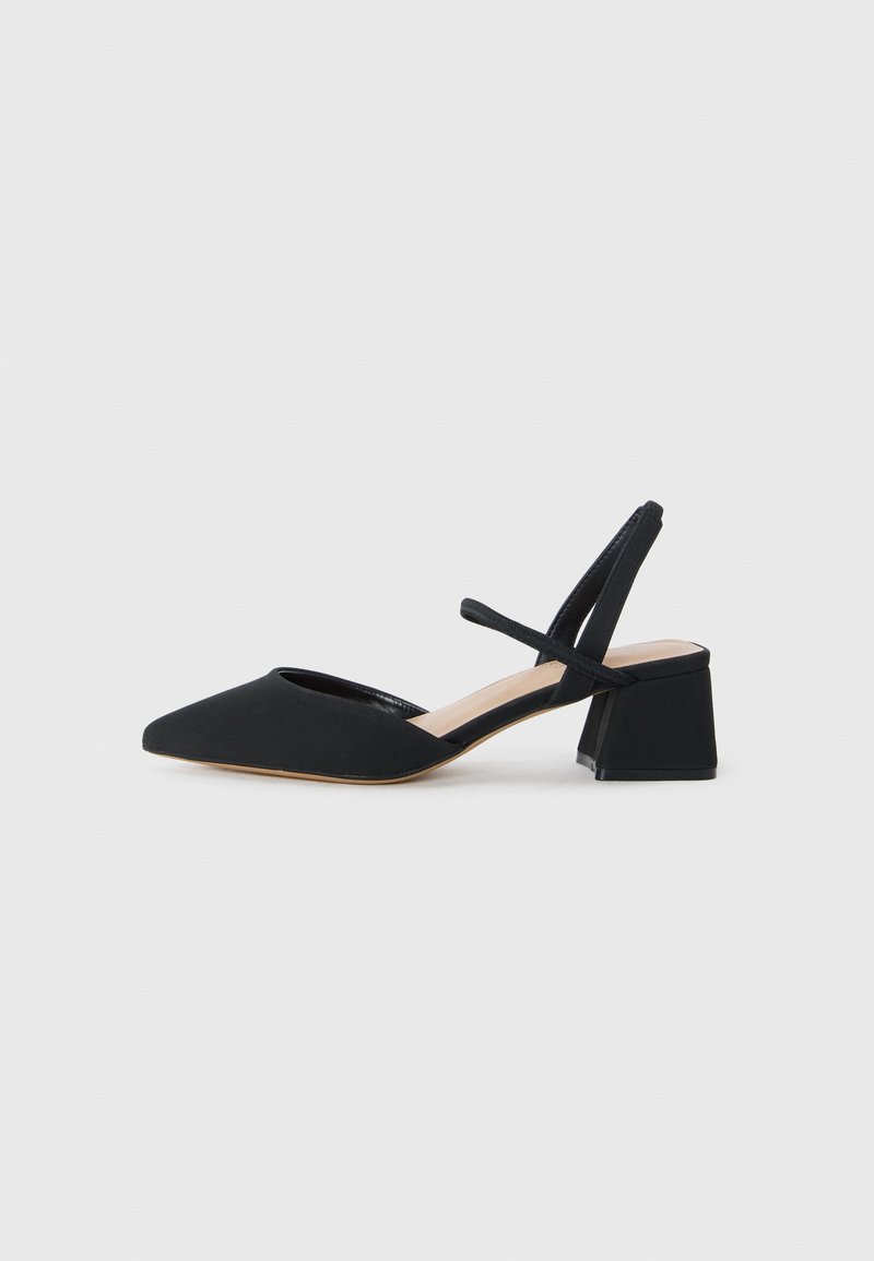 Escarpin noir à talon slingback avec un bout pointu, en tissu texturé, et un talon géométrique épais. Présente des brides croisées au niveau de la cheville.