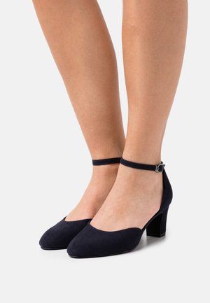 Granatowe zamszowe buty na obcasie z okrągłym noskiem i paskiem na kostce; mają blokowy obcas i gładką teksturę, co nadaje im elegancki wygląd.