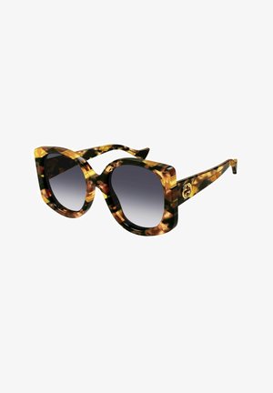 Schildpatt-Sonnenbrille mit übergroßen, quadratischen Gläsern, dunklem Verlaufstönung und schlanken Bügeln, die auf einer Seite ein goldenes Emblem tragen.