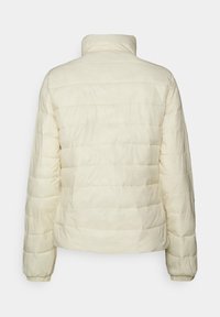 Pufferjack in ivoor met een gewatteerd ontwerp, hoge kraag en elastische manchetten. Glad textuur, lichtgewicht en uniforme stiksels.