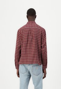 Rot und weiß karierter Hemd mit button-down Kragen, langen Ärmeln und lockerer Passform, aus einem leichten Baumwoll-Mix gefertigt.