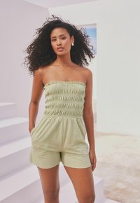 Mono verde sin tirantes con textura fruncida, busto ajustado y pantalones cortos relajados, que presenta bolsillos laterales y una tela ligera y transpirable.