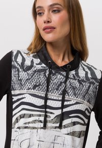 Un sweatshirt à capuche noir avec un devant texturé au motif varié, comprenant de la dentelle et des imprimés animaliers, ainsi qu'un col à cordon.