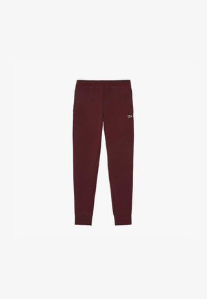 Bordeauxkleurige sweatpants van zachte stof met taps toelopende broekspijpen, een elastische tailleband en een klein groen merkimago op de bovenbenen.