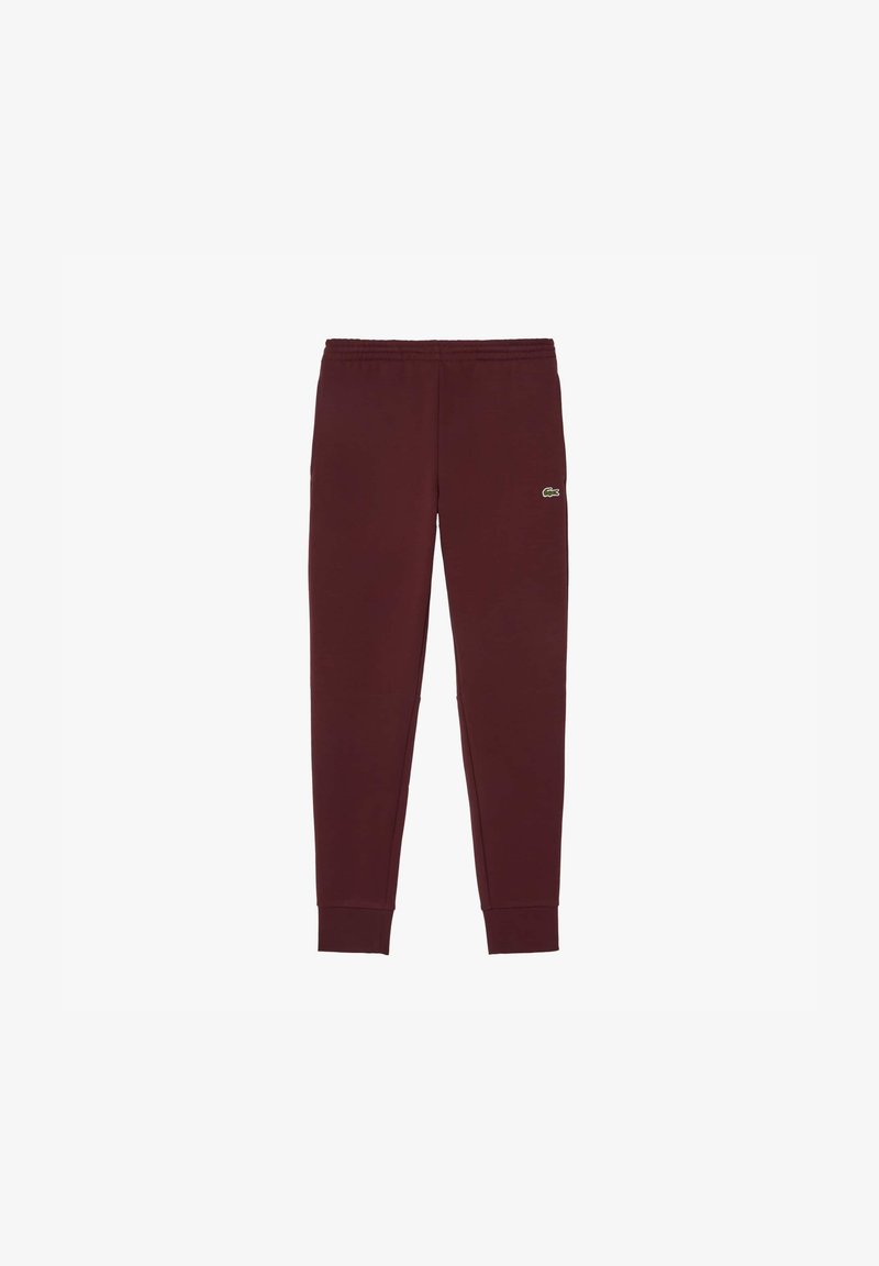 Burgundijas sporta bikses, kas izgatavotas no mīksta materiāla, ar sašaurinātiem galiem, elastīgu jostu un mazu zaļu zīmola logo augšstilbā.