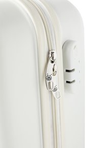 Valise rigide blanche avec une double fermeture éclair dotée d'un tirette en métal argenté et d'un cadenas combiné sur le côté. Texture lisse et bords arrondis.