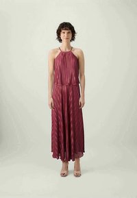 Robe halter plissée prune avec un design fluide jusqu'aux chevilles et une taille cintrée, présentant une texture lisse et légère.