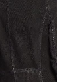 Svart perforerat läder med släta accenter, med regelbundna strukturerade sömmar och en texturerad finish. Sömdetaljer är synliga.