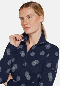 Marineblauer Quarter-Zip-Pullover mit einer Mischung aus einfarbigen und gestreiften kreisförmigen Mustern in Hellgrau. Weicher Stoff, lässige Passform, Stehkragen.