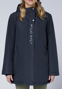 Dunkelblaue wasserdichte Jacke mit Kapuze, mit einem Reißverschluss vorne, zwei Seitentaschen und einem Logo "POLO SYLT" vertikal auf der Vorderseite.